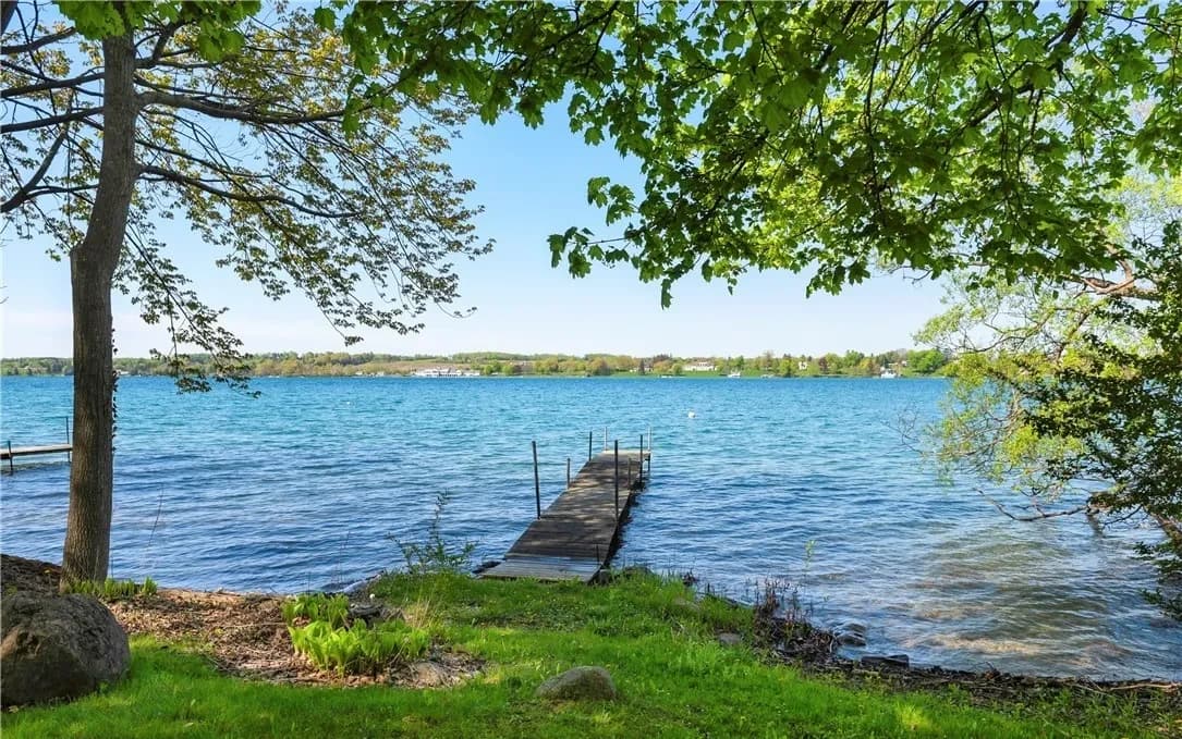 Clear Skaneateles Lake water and a dock framed by the Landing's trees